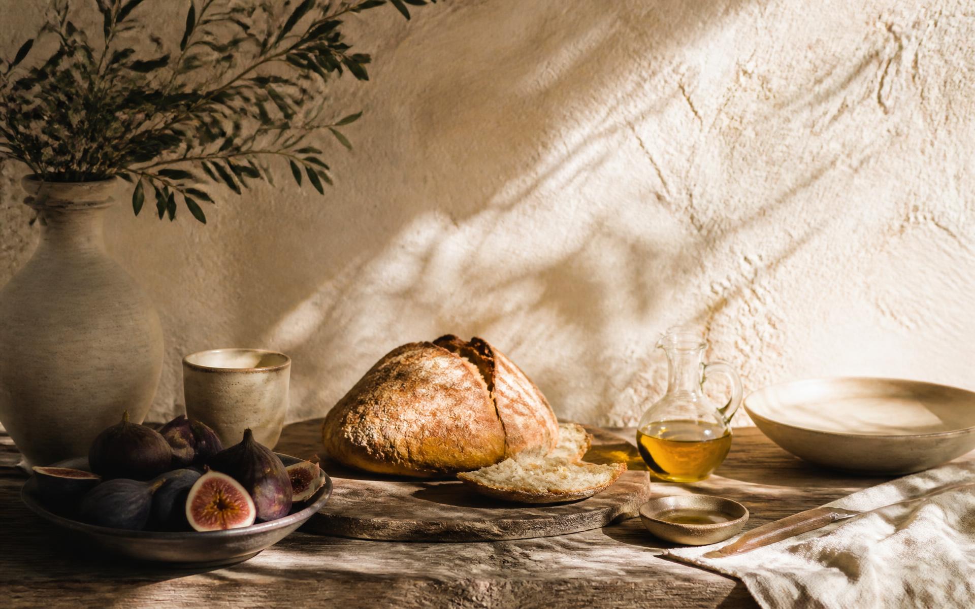 Bread, olive oil and ceramics on a wooden table in morning light
